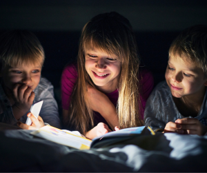 Noc Bibliotek w Kędzierzynie-Koźlu. dzieci czytające książki nocą w świetle nocnej lampki.